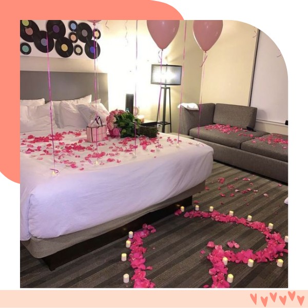 cama com pétalas de rosas e pedido de namoro no quarto