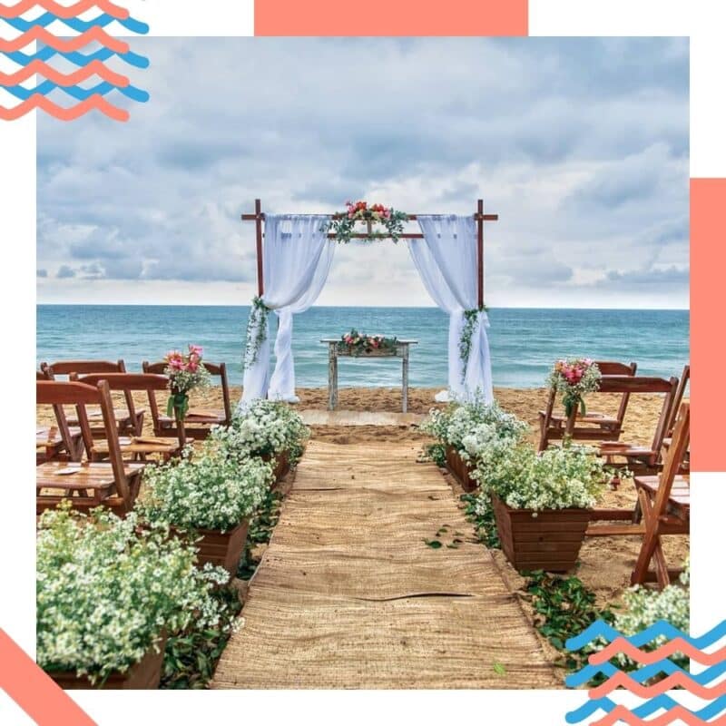 decoração de casamento na praia altar com cortinas brancas e flores verdes